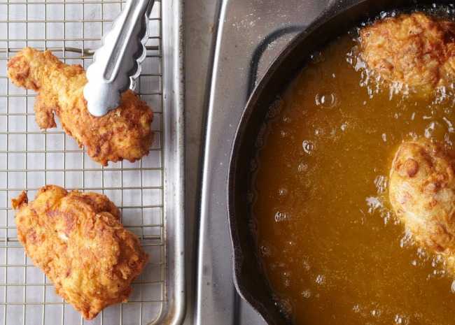 Pollo fritto dall'olio al rack con pinze